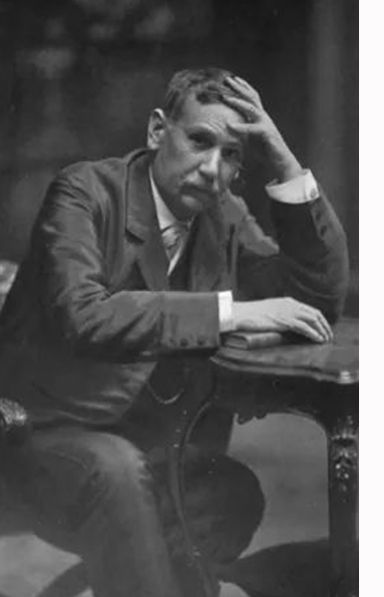 Benito Pérez Galdós sentado al lado de una mesa sobre la que apoya los dos brazos